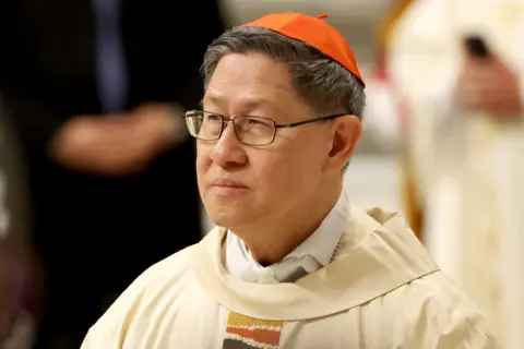 Getty Images Cardinal Luis Antonio Tagle wears a red cap on his head as he looks away from camera in a head and shoulders portrait, while he attends a Mass with newly appointed cardinals presided by Pope Francis at St. Peter